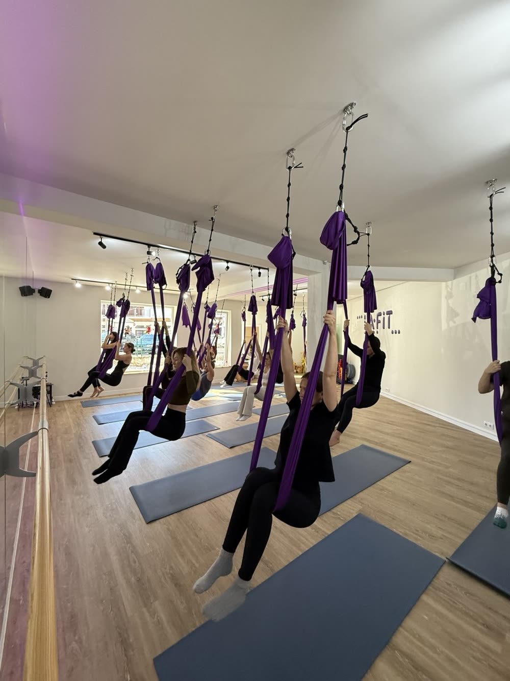 Група сидить у гамаках на початку заняття в студії LA fit